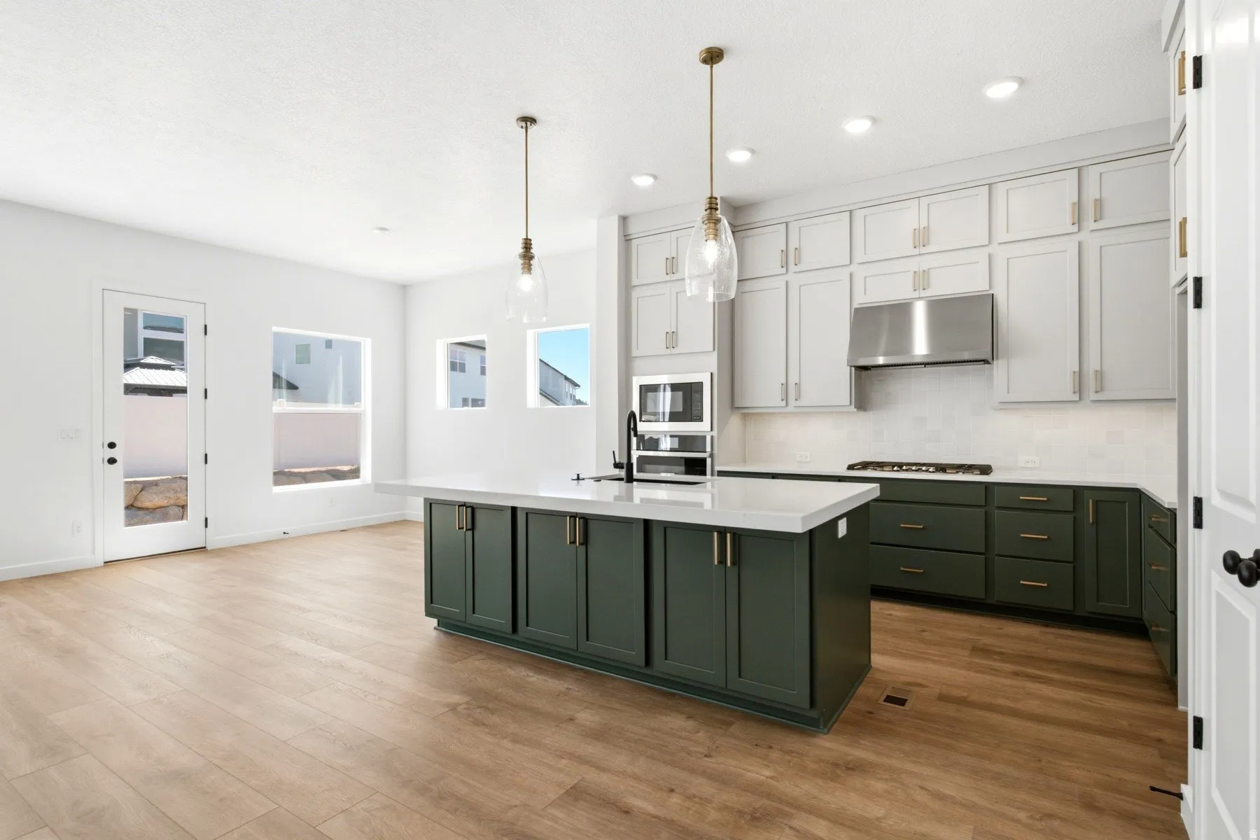 Kitchen featuring an expansive center island with pendant lighting, white countertops, two-tone cabinetry, and wood-finish flooring