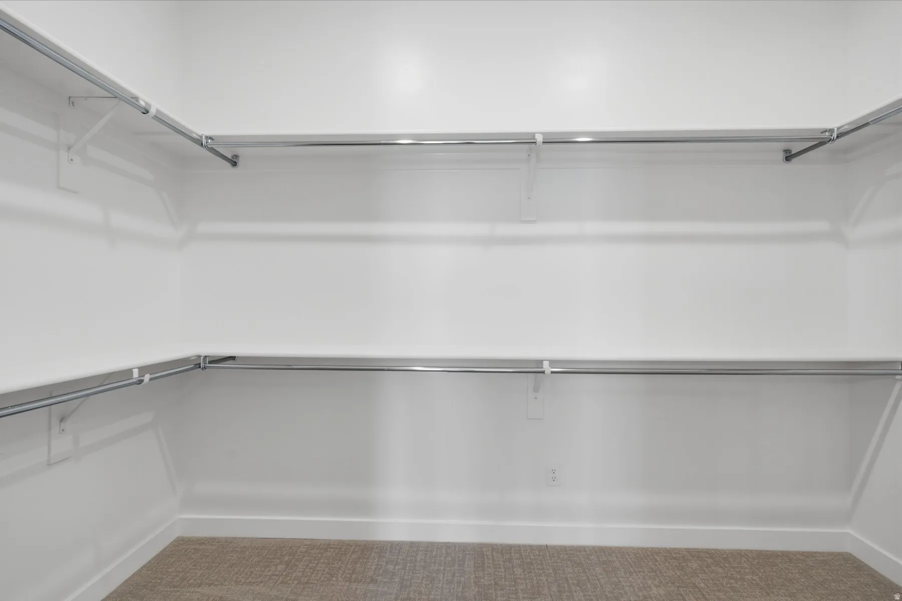 Walk-in closet with carpet flooring, white walls, and built-in chrome hanging rods