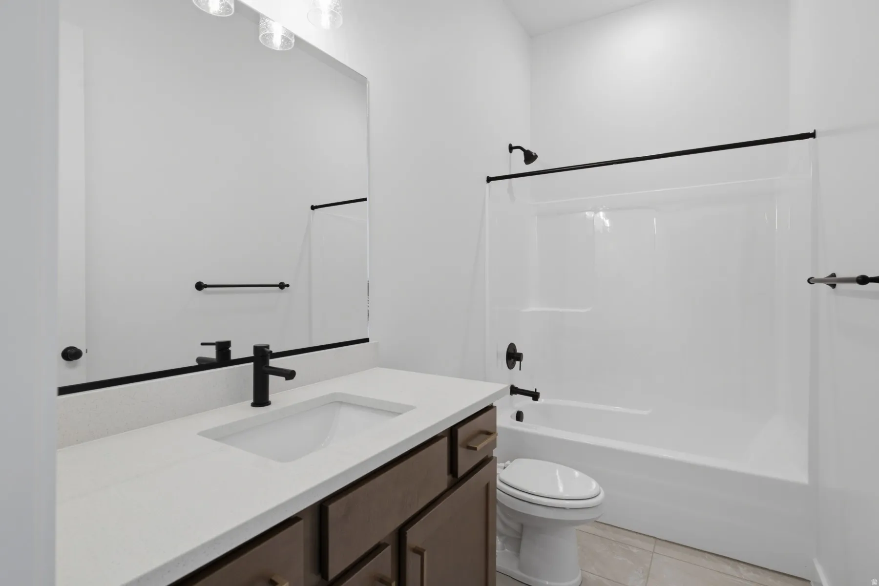 Modern bathroom featuring a wood-finish vanity with dual-sink configuration, white quartz countertop, matte black hardware and faucet, frameless glass shower enclosure with matching matte black fixtures, and ceramic tile flooring