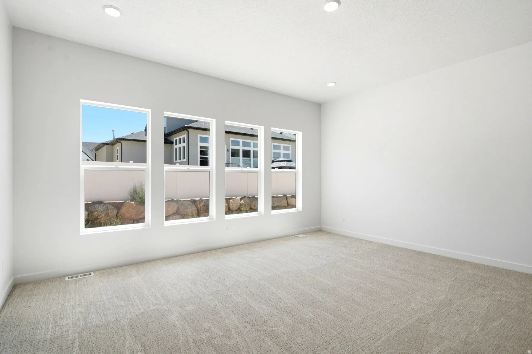 Four individual windows, recessed ceiling lighting, and light-toned carpeting
