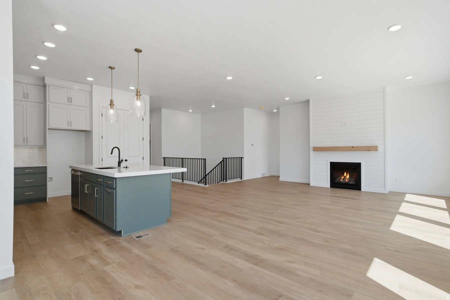 Open-concept living space featuring wood-finish flooring, recessed lighting, and a kitchen island with a built-in sink