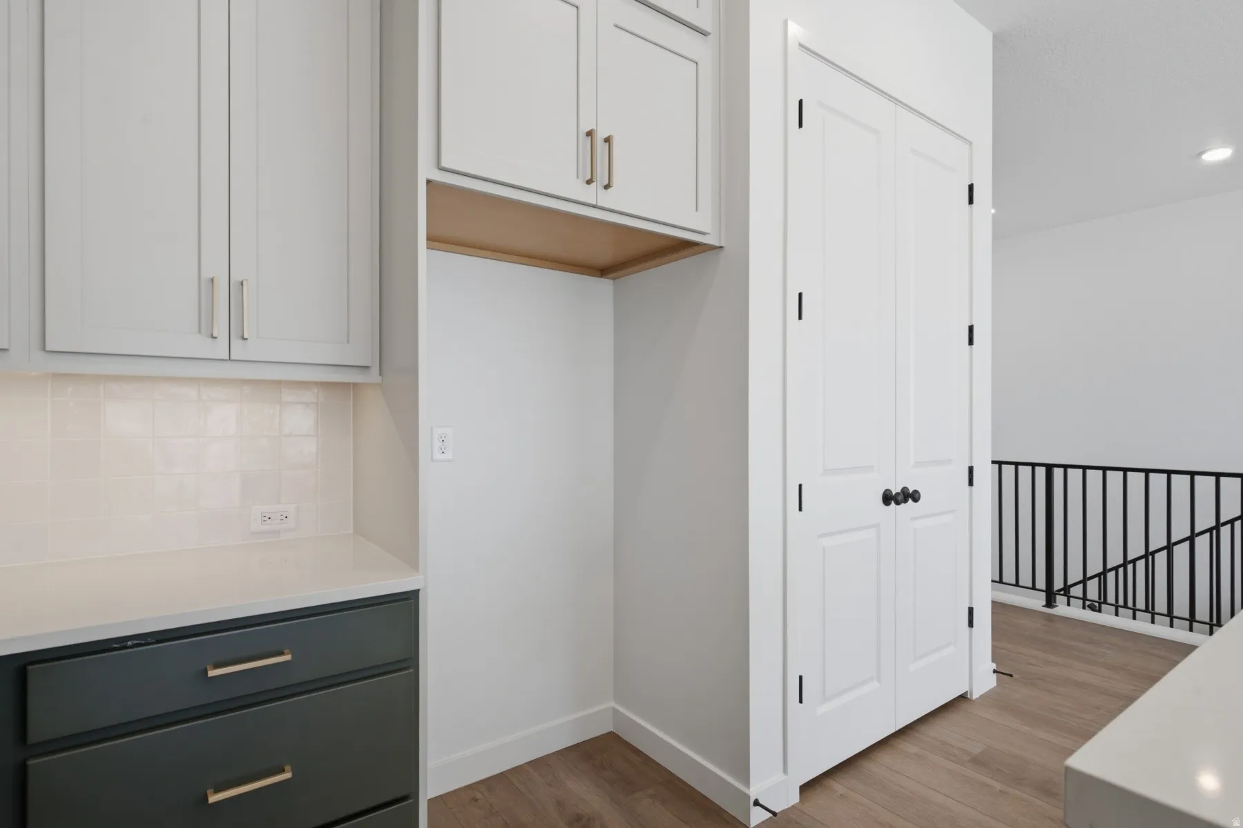 Kitchen area with light gray upper cabinetry, dark gray lower cabinetry, and gold-tone hardware