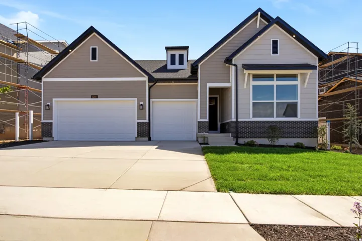 Contemporary exterior with a two-car garage, dark trim details, a prominent dormer, and a well-maintained lawn