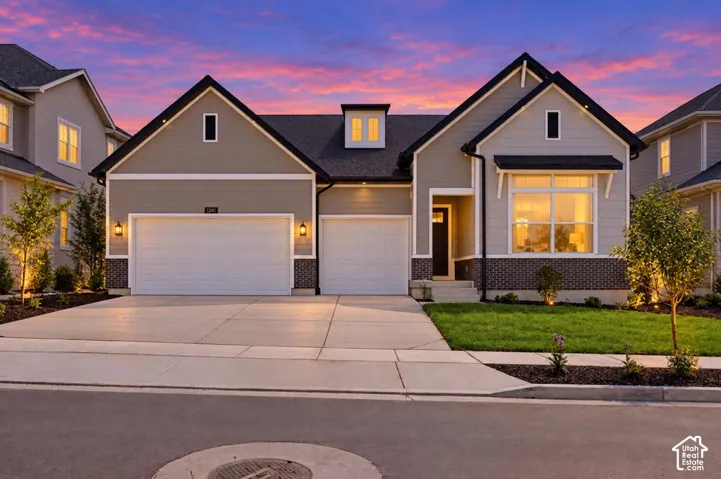 Contemporary exterior with gray siding and dark trim, two-car garage, brick accents, and a covered entry
