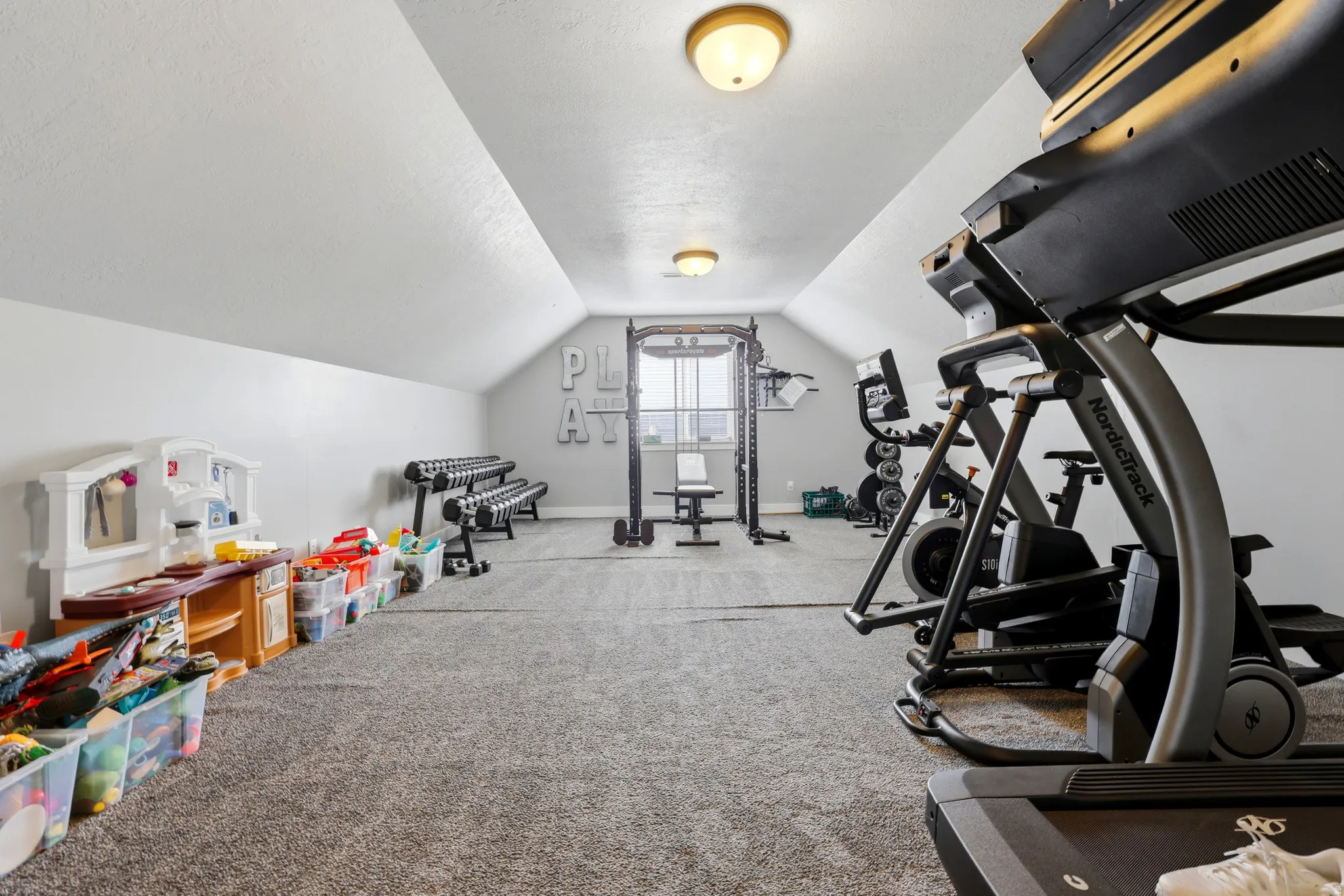 Expansive bonus room featuring sloped ceilings, recessed window, and gray carpeting