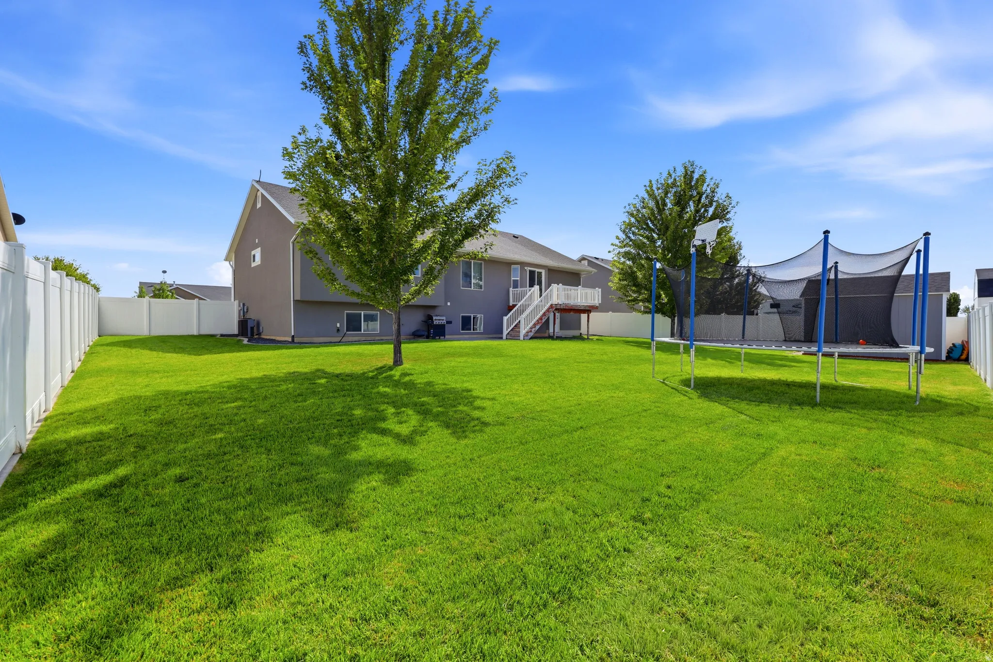 Expansive grassy yard with mature trees and perimeter fencing