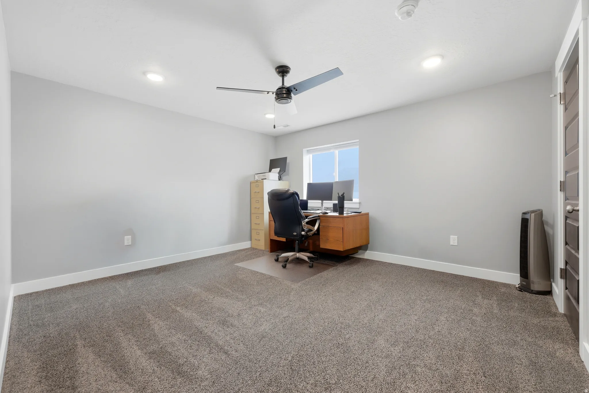 Neutral-toned carpeting, light gray wall finishes, and a contemporary ceiling fan with integrated lighting