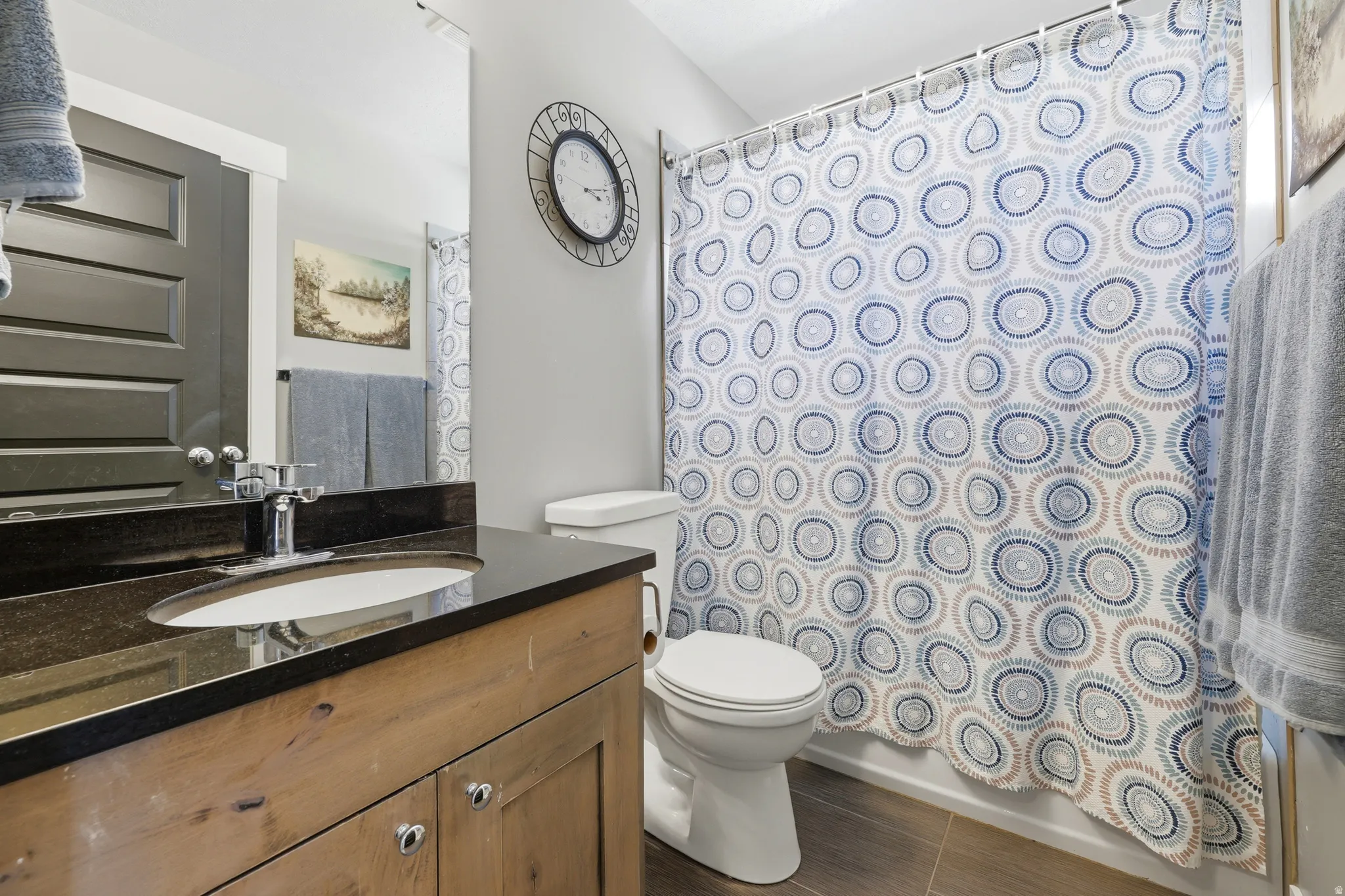 Wood-finish vanity with a black countertop and undermount sink