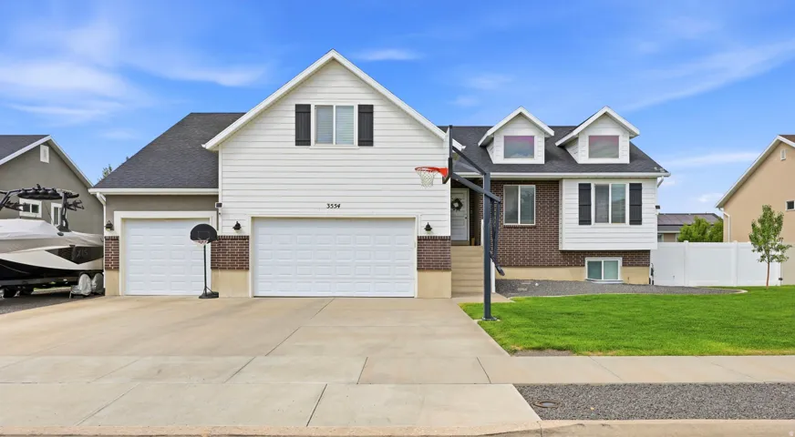 Two-story residence featuring white siding, dark brick accents, a two-car garage, and a concrete driveway