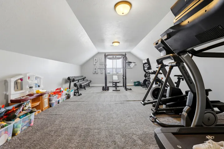 Expansive bonus room featuring sloped ceilings, recessed window, and gray carpeting