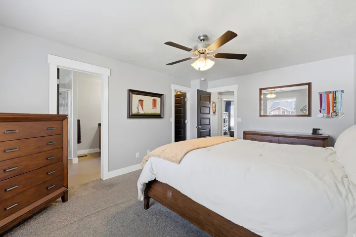 Ceiling fan with integrated lighting, light gray wall paint, dark wood-finish interior doors, white trim, and carpeting