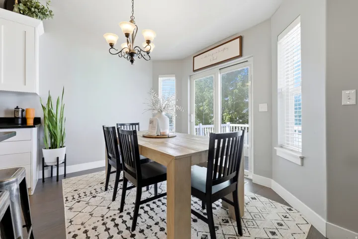 Dining area with wood-finish flooring, white cabinetry, a sliding glass door, and a multi-pane window