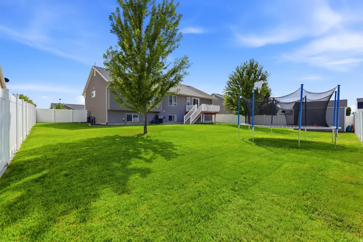 Expansive grassy yard with mature trees and perimeter fencing