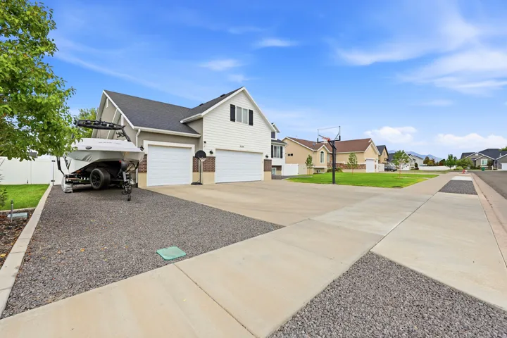 Two-story residence featuring a two-car garage, an additional single-car garage, and a gravel parking area