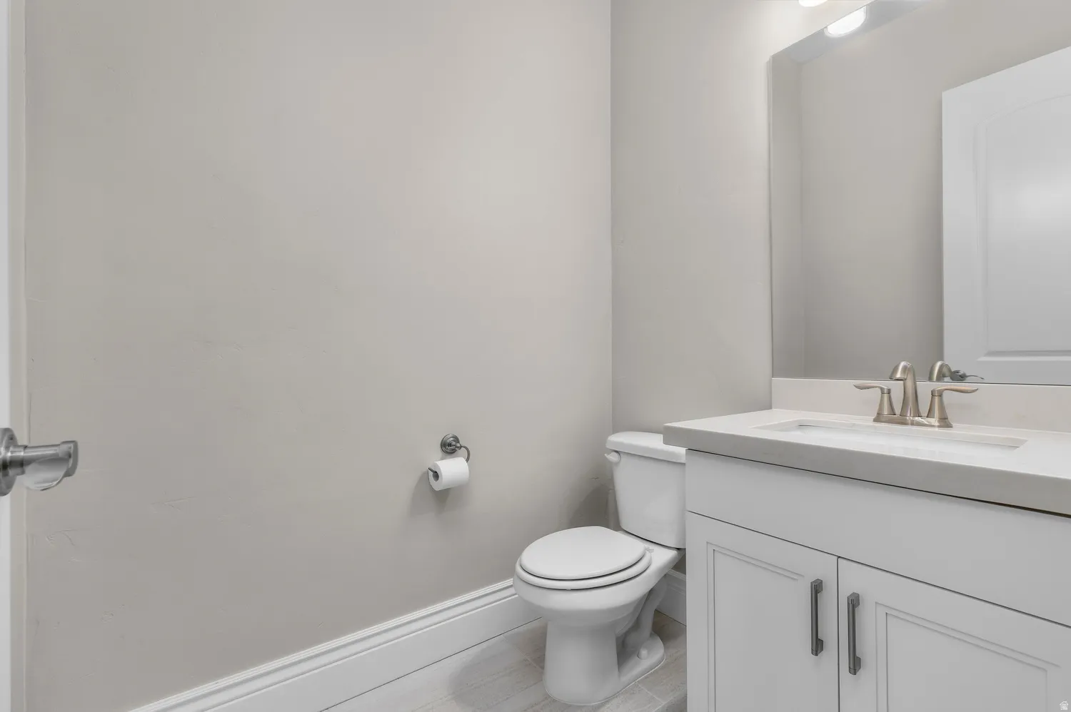 White vanity with shaker-style cabinetry, an integrated sink, and a brushed nickel faucet