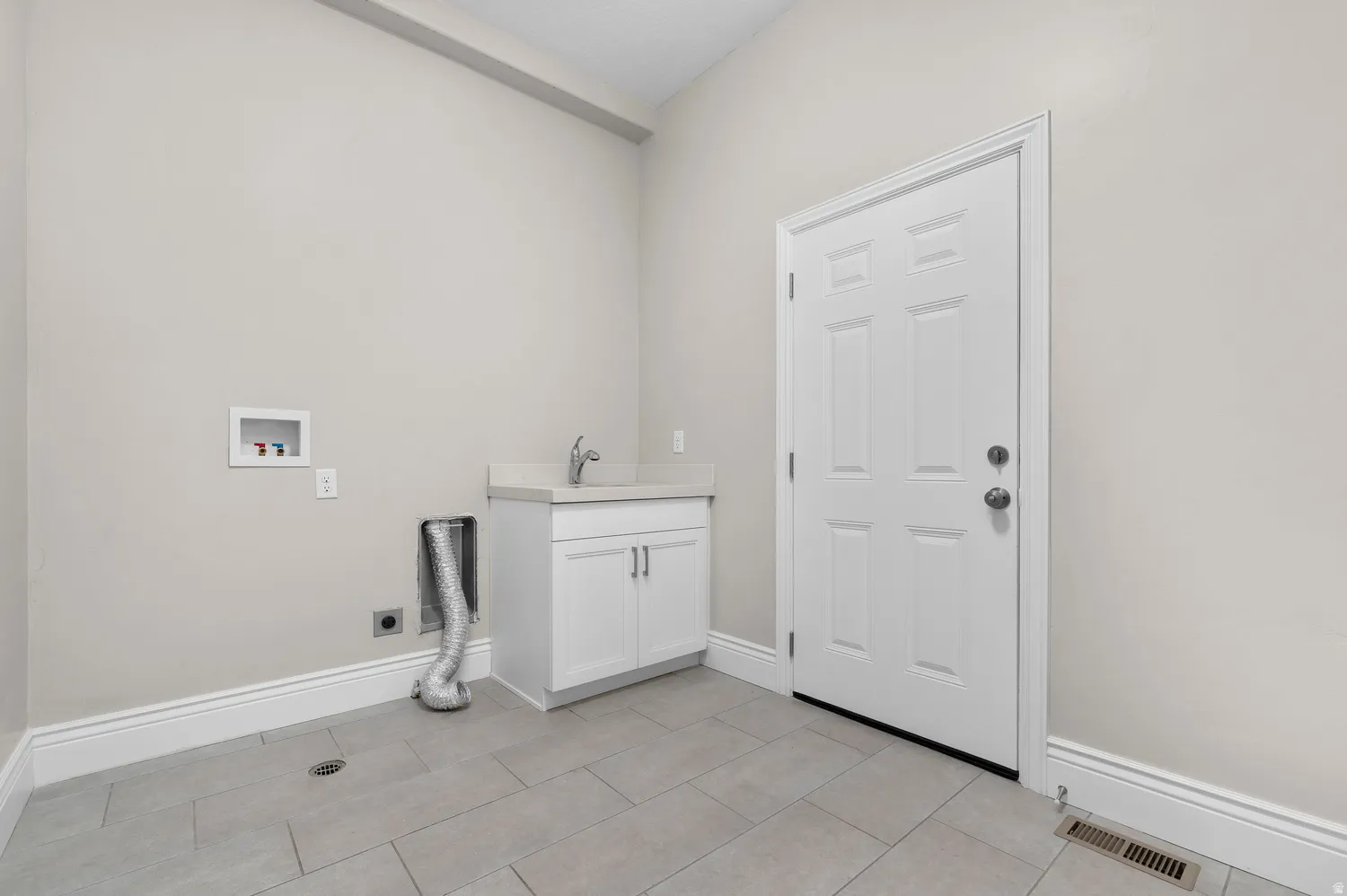 Laundry area featuring a utility sink, white cabinetry, a light-toned countertop, and tile flooring