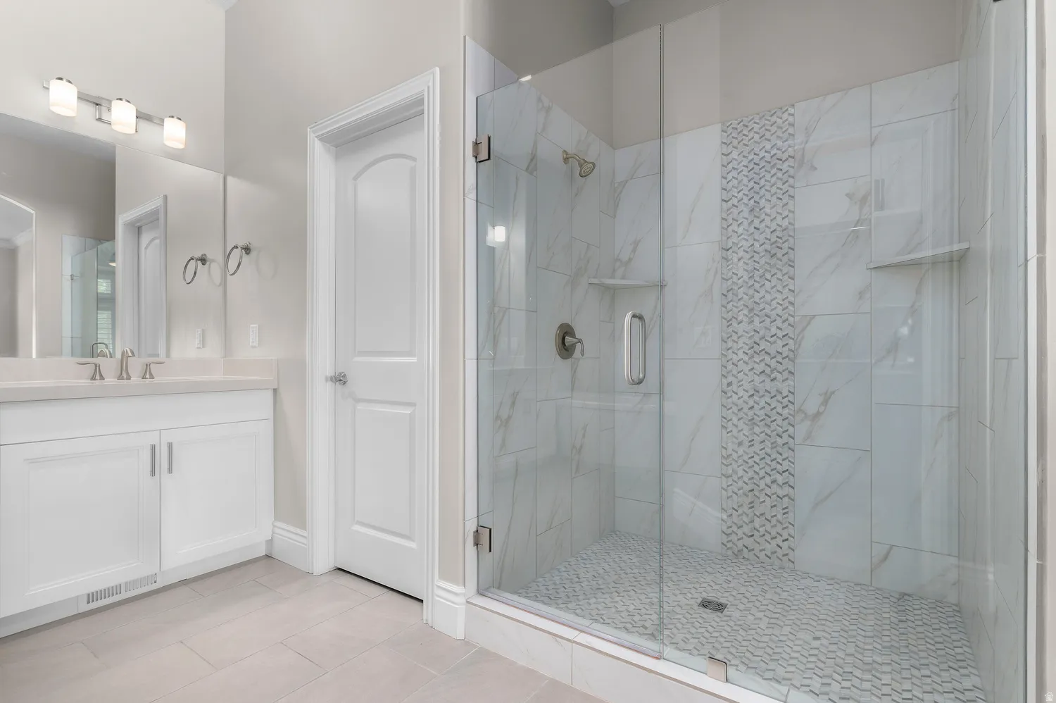 Glass-enclosed shower with a decorative tile accent wall and built-in shelving