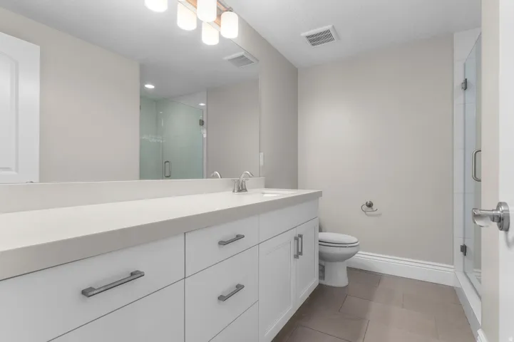 Dual vanity with a stone-finish countertop, white cabinetry, and brushed nickel hardware