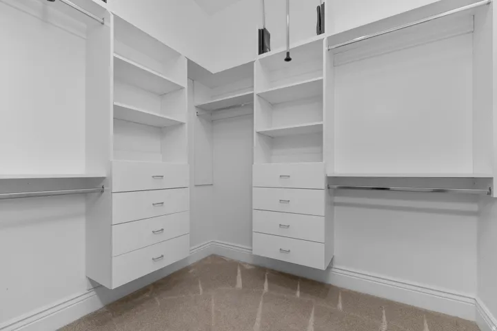 Built-in closet system with shelving, integrated drawers, chrome hanging rods, and carpet flooring