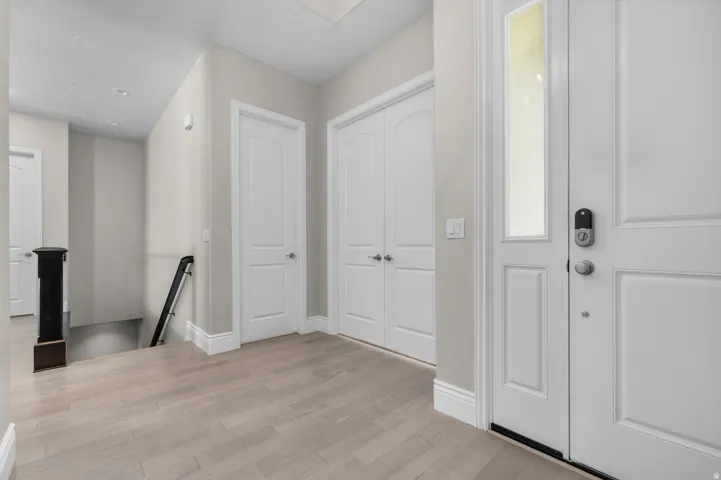 Light-toned wood-finish flooring, white paneled doors, and a staircase with a dark railing