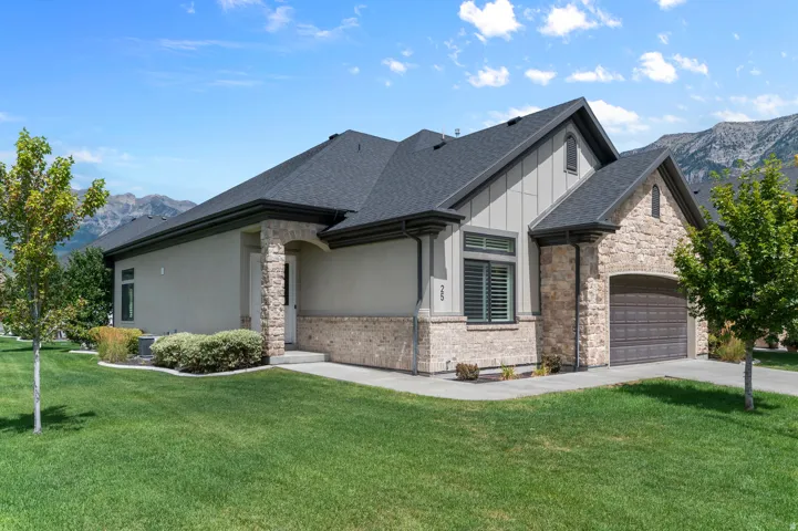 Stone and stucco exterior with a dark shingle roof