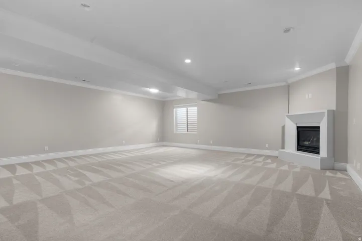 Expansive room featuring recessed lighting, a corner fireplace, a window with horizontal blinds, and crown molding