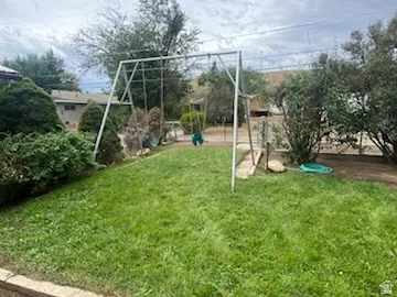 Expansive grassy yard area with mature perimeter landscaping and a concrete-edged garden bed