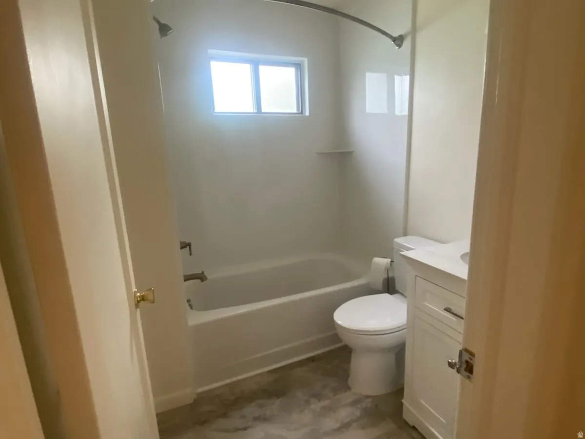 Bathroom featuring a white bathtub, toilet, and vanity with a rectangular sink