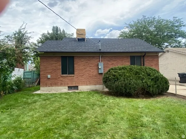 Brick exterior with a dark shingle roof, foundation planting, and a manicured lawn