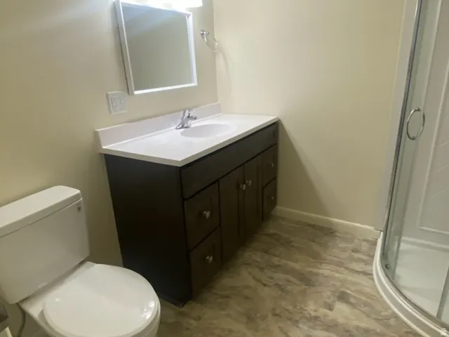 Vanity with a white countertop and integrated sink, chrome faucet, wall-mounted mirror, and three-light fixture
