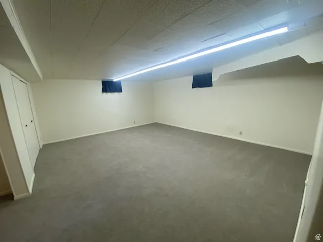 Spacious room with light gray carpeting, white walls, built-in bi-fold doors, and a drop ceiling