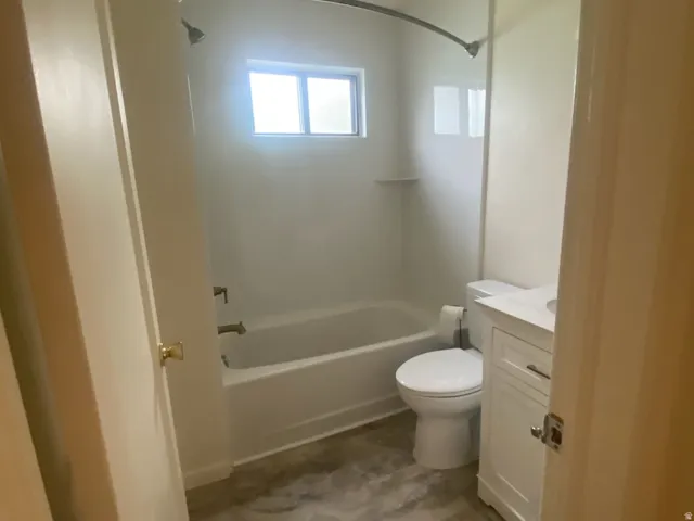 Bathroom featuring a white bathtub, toilet, and vanity with a rectangular sink