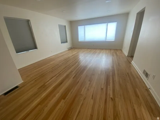 Hardwood flooring, recessed lighting, multiple windows with blinds, white walls, and white trim