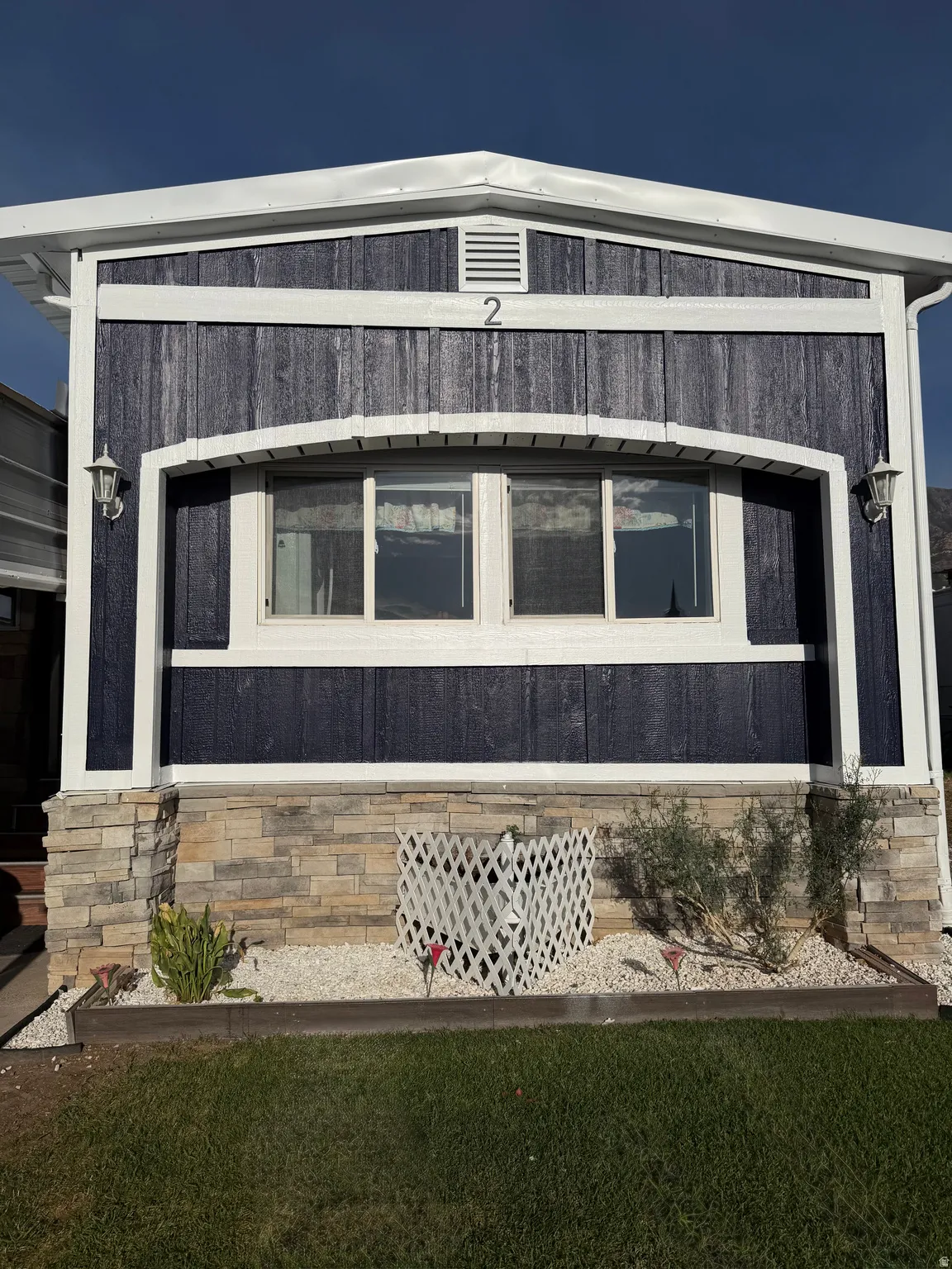 Front exterior with dark blue vertical siding and white trim