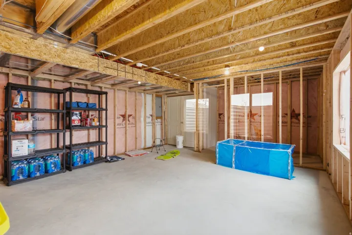 Unfinished basement featuring exposed wood joists and framed walls, offering customization potential