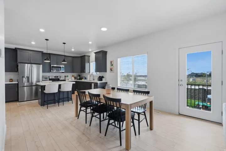Kitchen and dining area featuring light wood-finish flooring, dark cabinetry, stainless steel appliances, and a built-in kitchen island