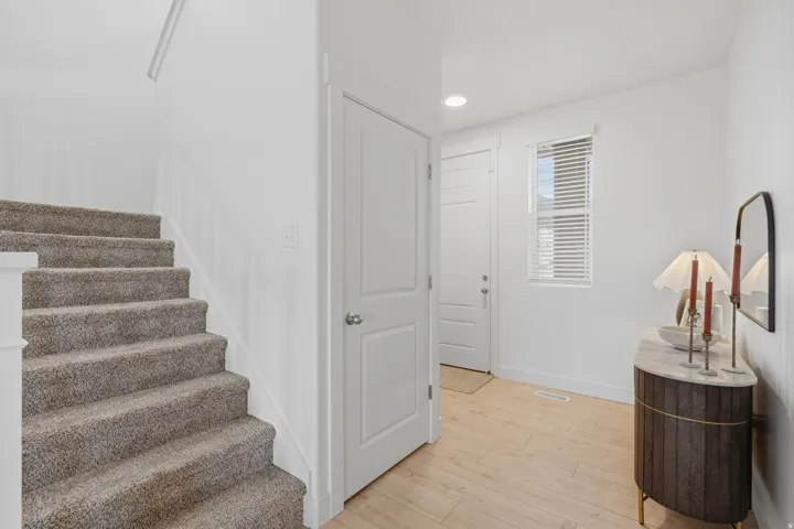 Carpeted staircase, wood-finish flooring, white walls, white doors, and a window with blinds