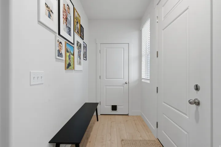 Light wood-finish flooring with white trim, white paneled doors, and a window with horizontal blinds