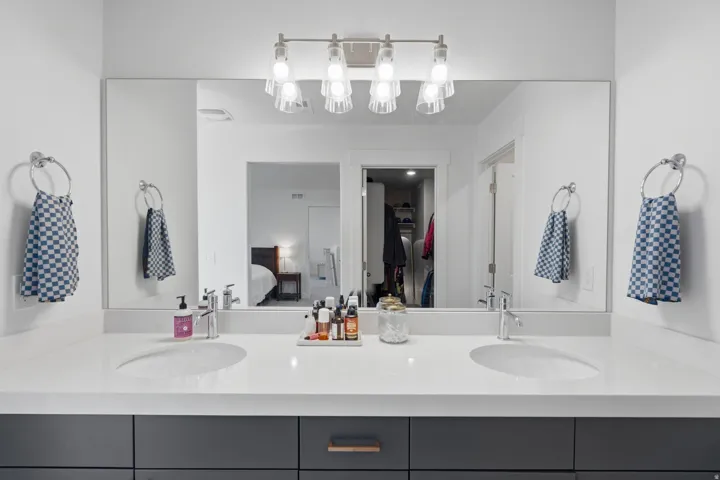 Dual vanity with undermount sinks, white countertop, and dark cabinetry with drawer pulls