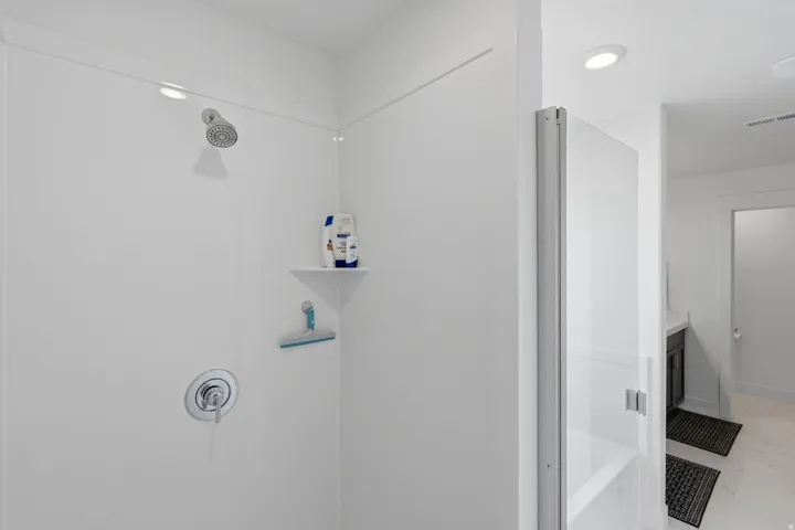 White shower surround with a built-in corner shelf and polished chrome fixtures