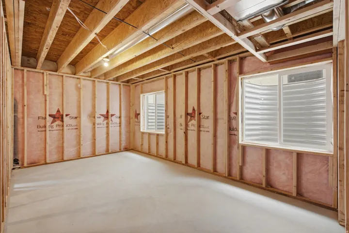 Unfinished basement with concrete flooring, framed walls, and two egress windows