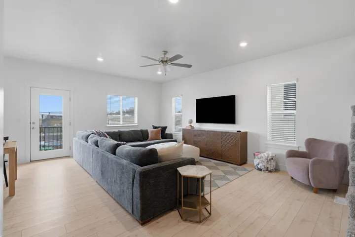 Recessed lighting, wood-finish flooring, ceiling fan, multiple windows with blinds, and a built-in media console