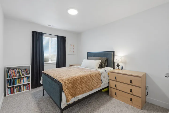 Carpeted bedroom with a window featuring horizontal blinds, and an overhead circular light fixture