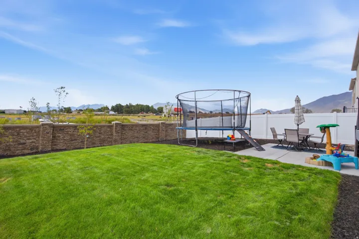Expansive lawn area, stone-finish privacy wall, concrete patio, and white vinyl fencing