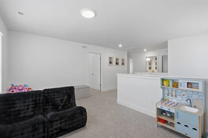 Carpeted flooring, white walls, built-in lighting, white trim, and a white interior door