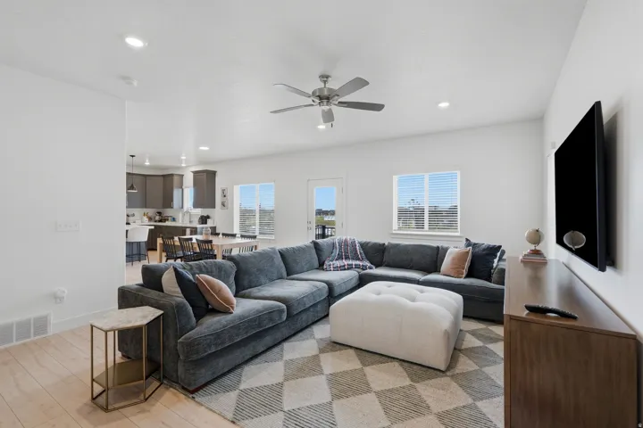 Recessed lighting, wood-finish flooring, ceiling fan, multiple windows with blinds, and a glass-paneled door