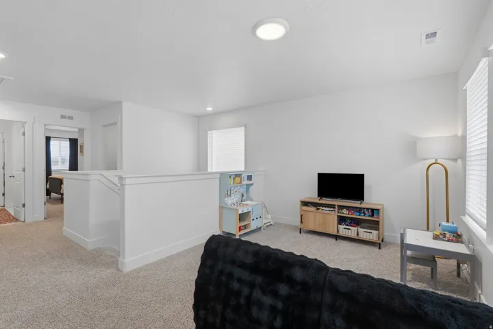 Loft area with light-colored carpeting, white painted walls, and a recessed ceiling light fixture