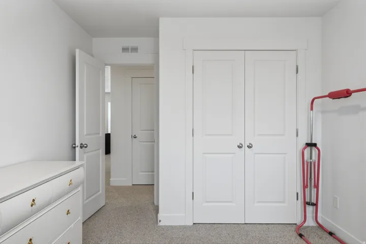 White paneled bi-fold closet doors, light neutral carpeting, and white interior doors