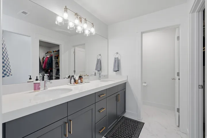 Dual vanity with white countertops, undermount sinks, and gray cabinetry