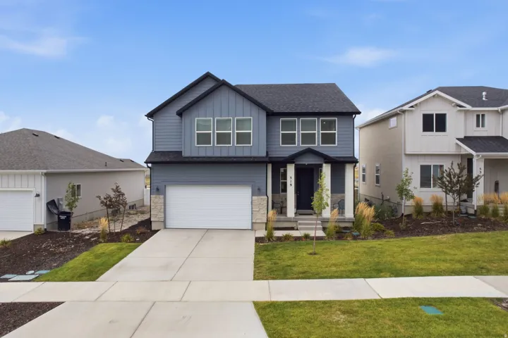 Contemporary two-story exterior with a two-car garage, dark gray siding, and stone accents